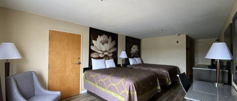 A hotel room with two beds, a desk, a chair, and a bathroom.
