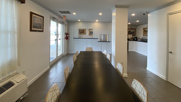 A spacious dining area with a long table and chairs, a kitchen in the background, and a door leading to another room. - Harrington Welcome Inn (Harrington)