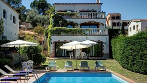 A two-story building with a swimming pool, outdoor seating, and a view of the sea.