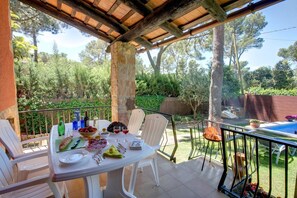 Enjoy a meal under the pergola, surrounded by lush greenery and a serene pool view.