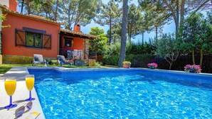 A swimming pool with two lounge chairs and a table with drinks and sunscreen. - Níspero - Two Bedroom Villa, Sleeps 4 (Begur)
