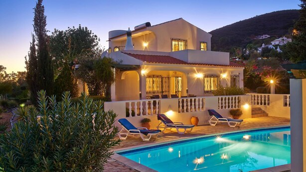 Una casa de dos pisos con piscina, mobiliario exterior y vistas del paisaje circundante.