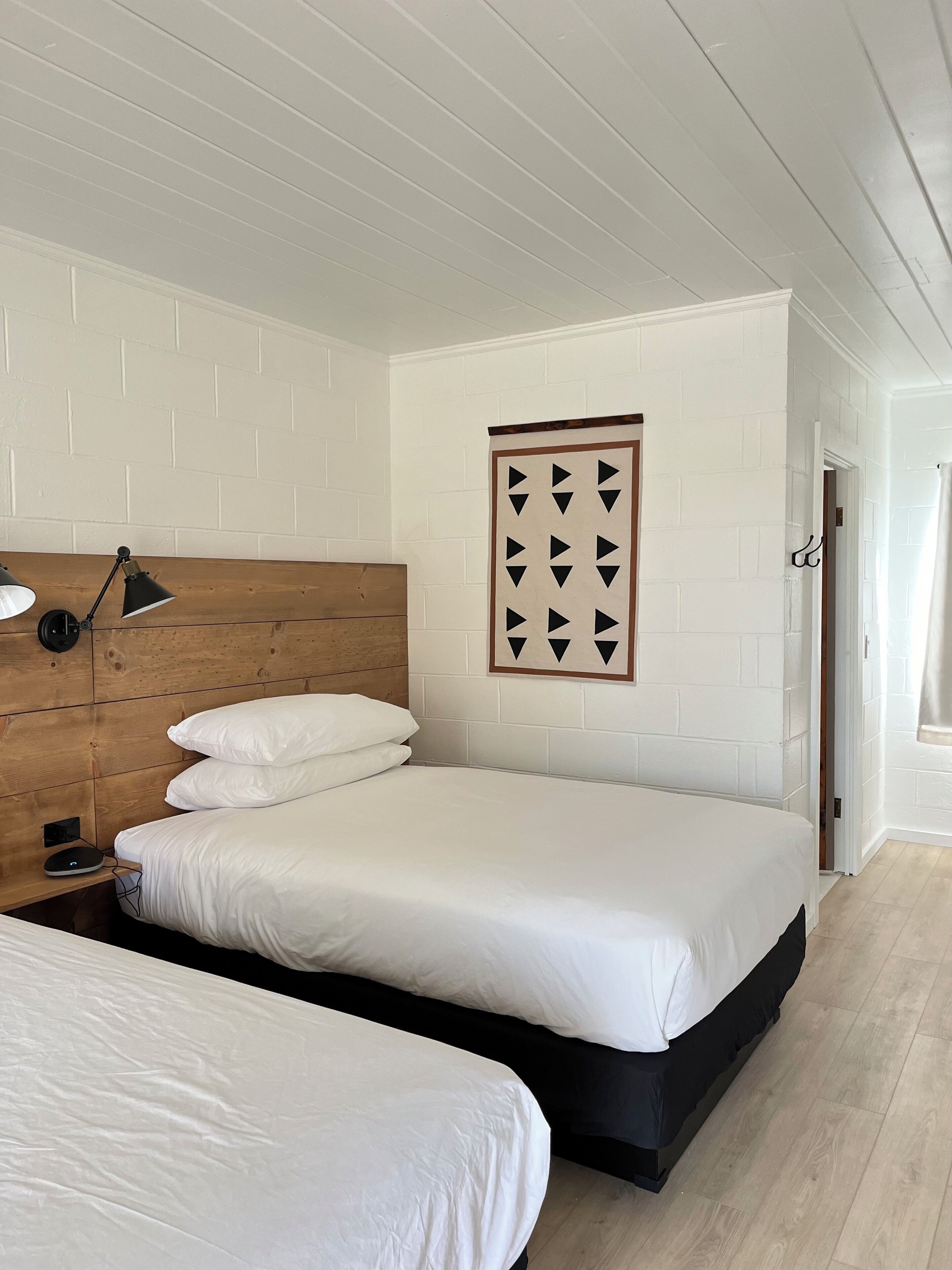 Un dormitorio con cabecera de madera, un cuadro colgado en la pared y una lámpara de noche.