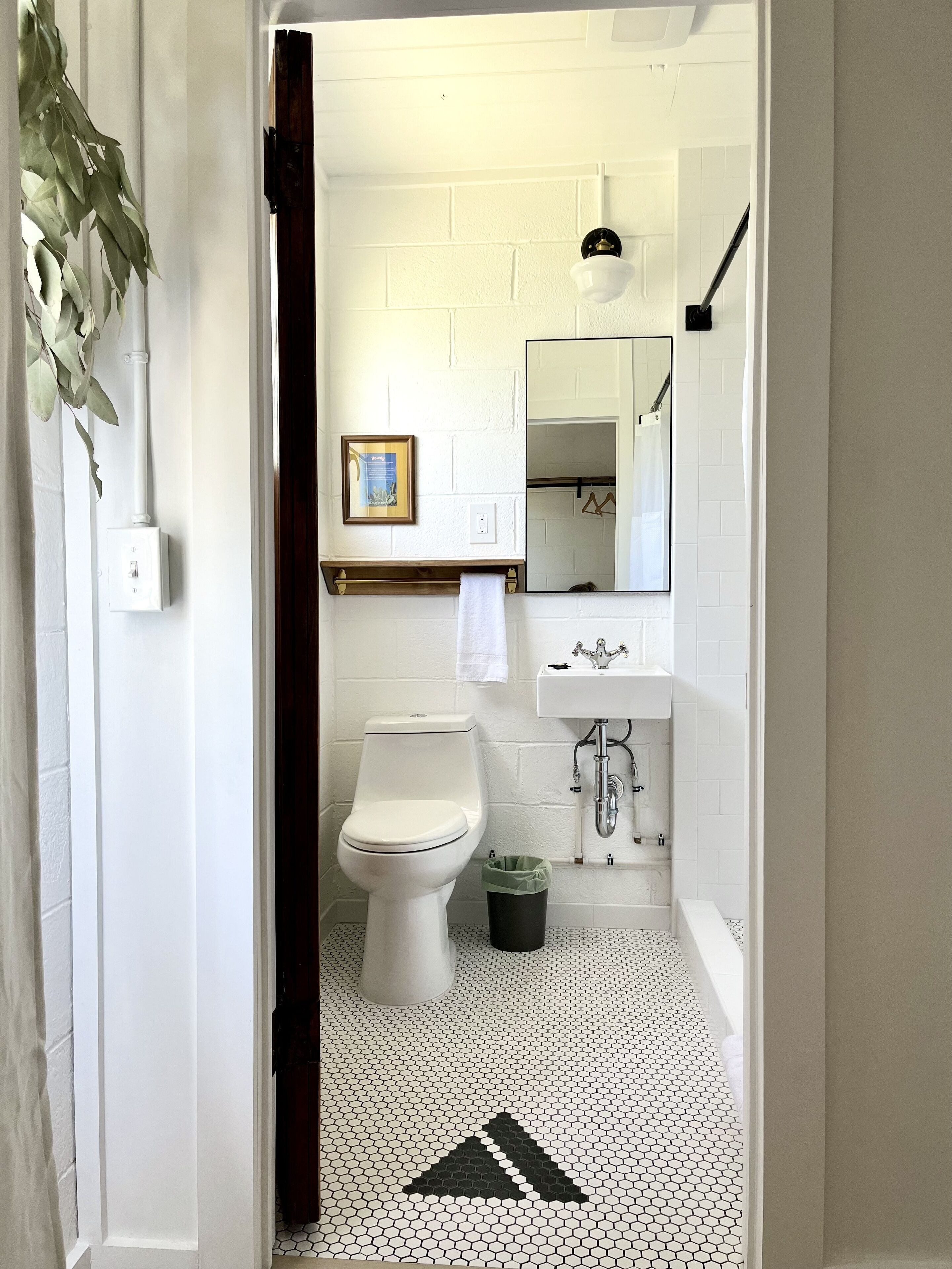 Un baño con inodoro, lavamanos, espejo y suelo de baldosas.