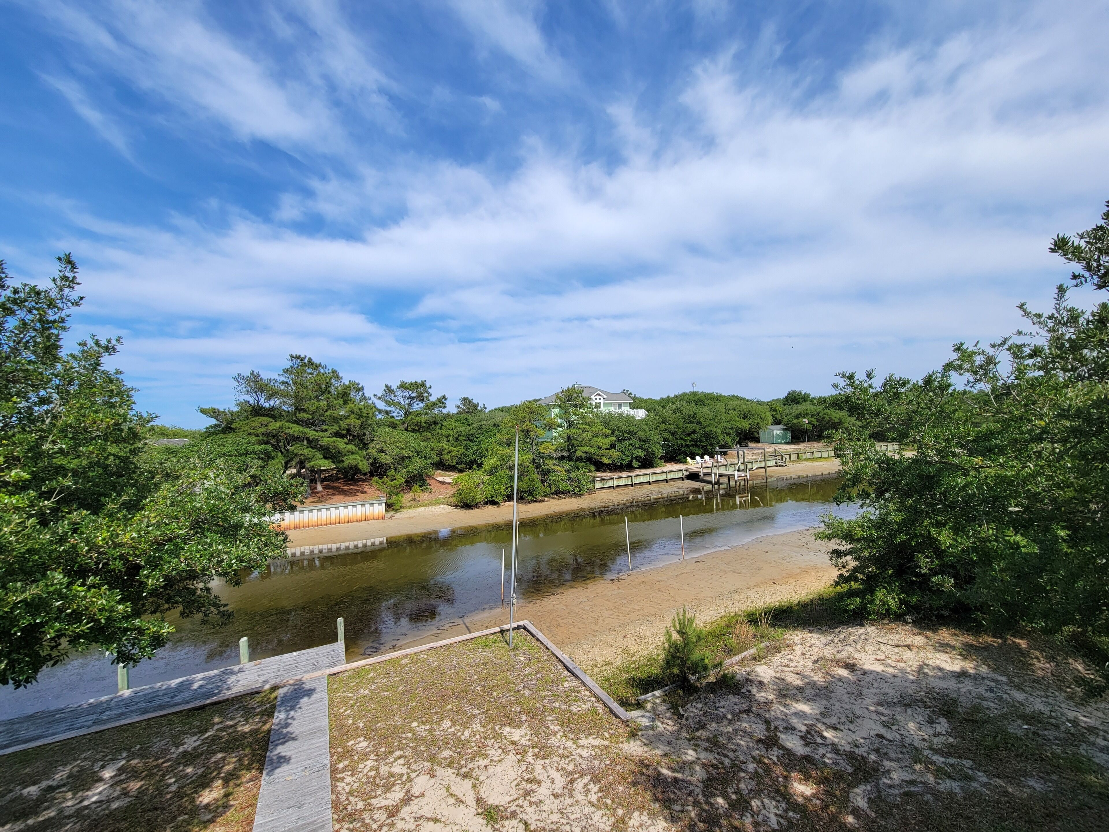 A riverside walkway with a wooden deck, surrounded by dense greenery and trees.