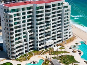 Un hôtel moderne à plusieurs étages, doté d’une piscine sur le toit et situé en bord de mer.