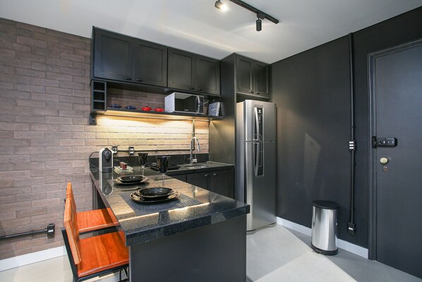 A modern kitchen with dark cabinetry, a stainless steel refrigerator, and a microwave.