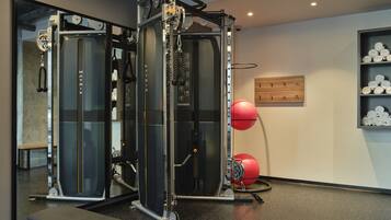 Ein Fitnessraum mit Kraftgeräten, einer Bank und einem roten Trainingsball.