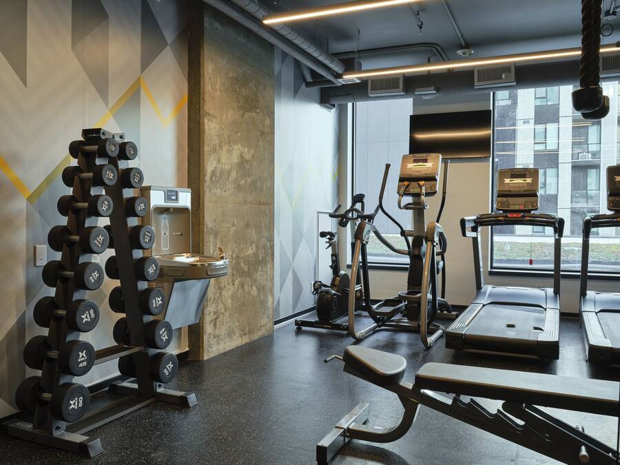 Un gimnasio con equipo de ejercicios, incluyendo mancuernas, cinta de correr y bicicleta estática.