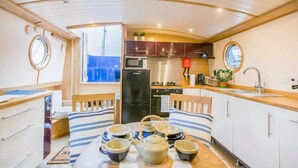 Cocina compacta con refrigerador, microondas y estufa. Cuenta con un comedor con mesa para dos personas y un ventanal con vistas al exterior.