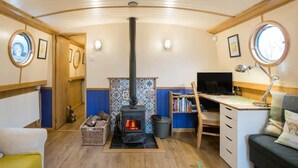 Un interior acogedor con un estufa de leña, un escritorio con computadora y una zona de estar confortable.