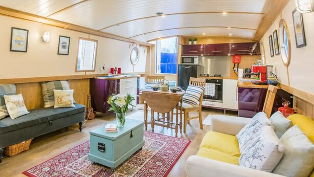 Un espacio habitable compacto con sofá, mesa de comedor y kitchenette.
