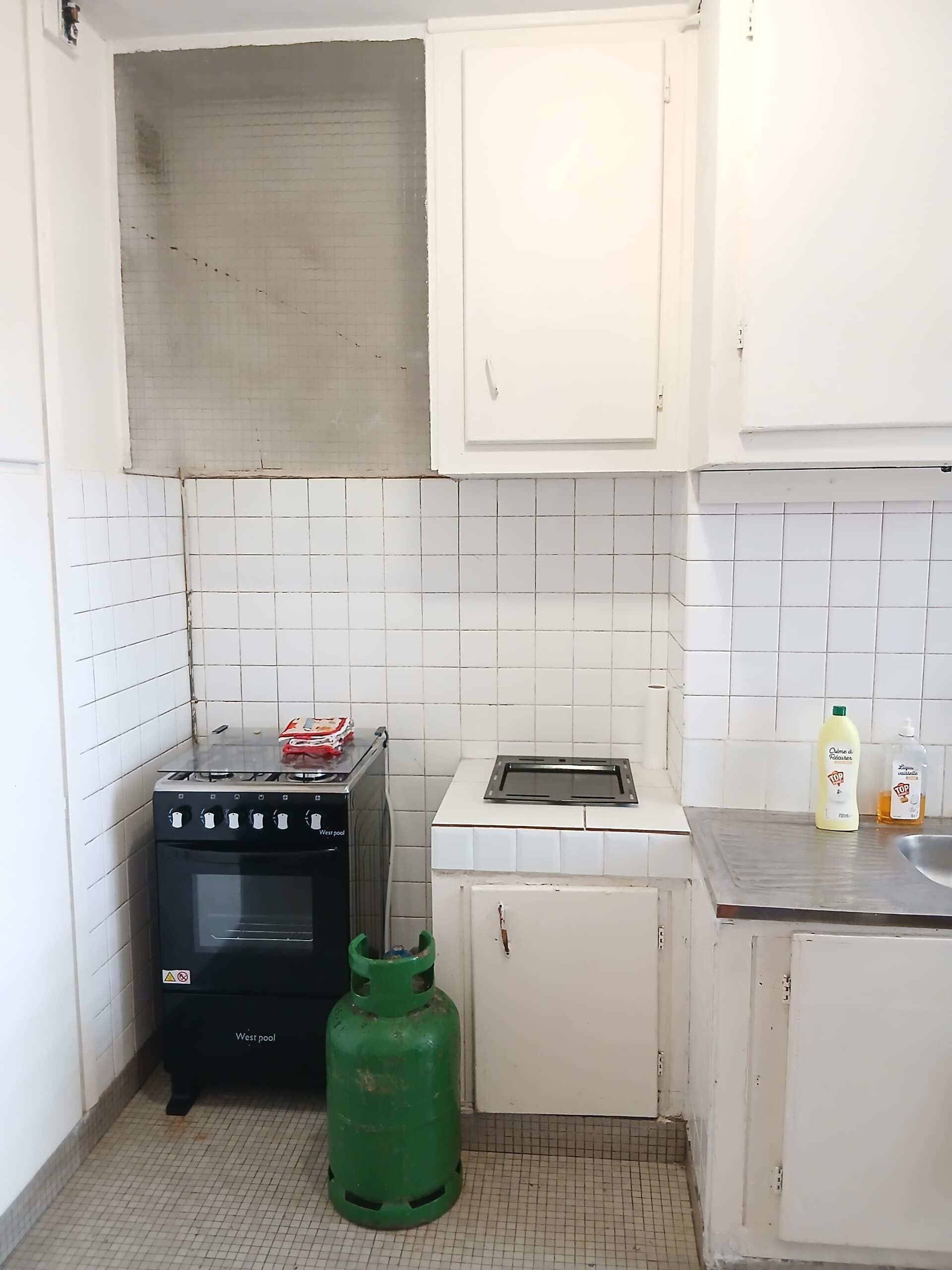 Eine kleine Küche mit Gaskochfeld, Toaster, Gasflasche und Spüle.