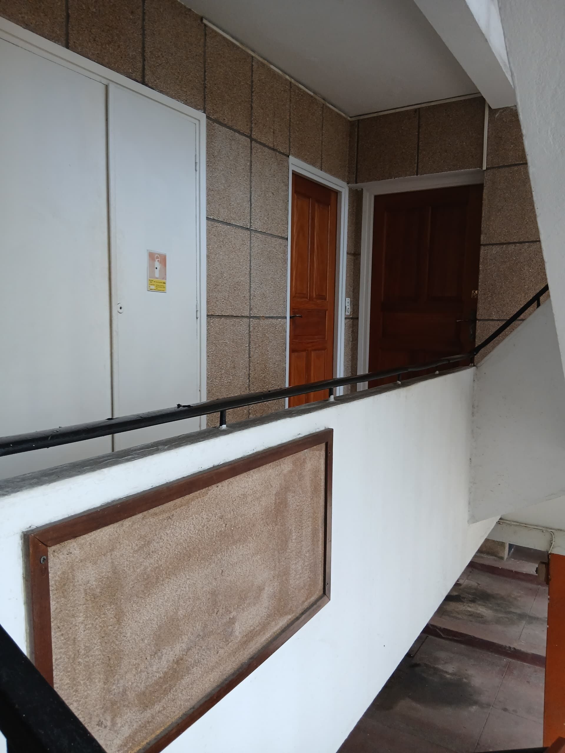 A staircase with a handrail, a white door, and a brown door.