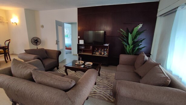 Ein Wohnzimmer mit braunen Sofas, einem Couchtisch, einem Fernseher und einem Bücherregal.