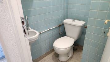 A small bathroom with a white toilet, a white sink, and blue tiled walls.