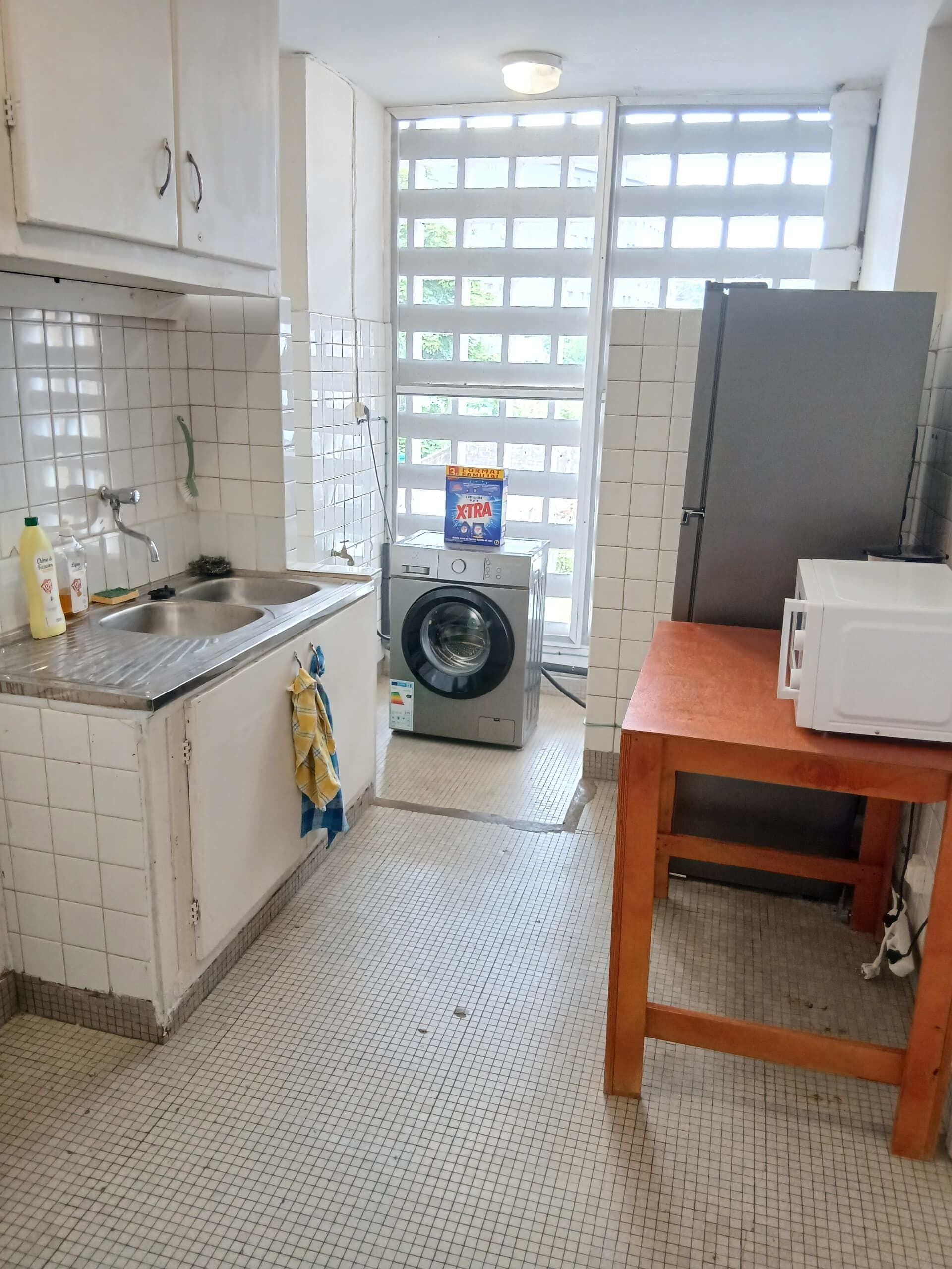 A small kitchen with a washing machine, a sink, and a microwave.