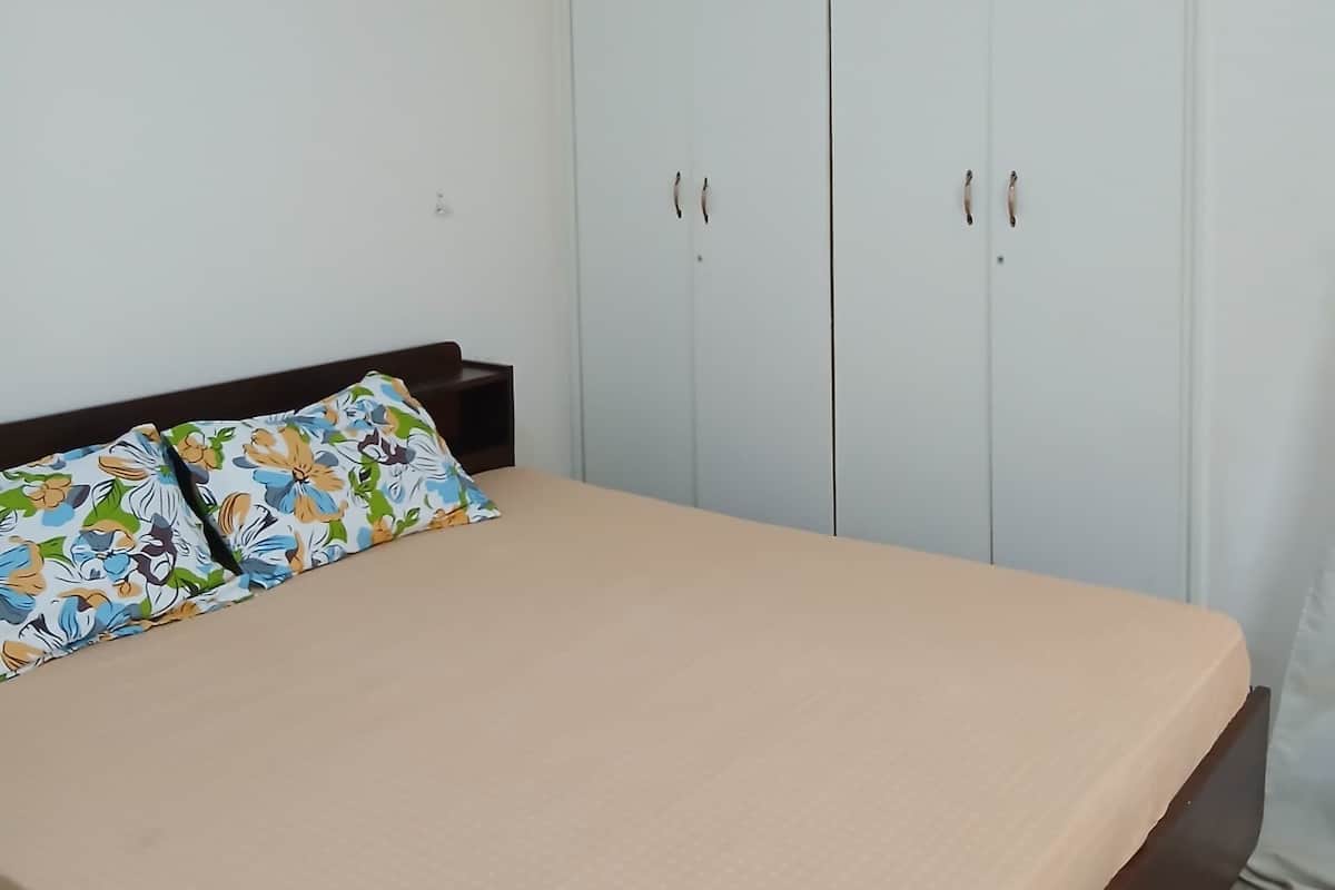 Une chambre à coucher comprenant un lit, une armoire et un appareil de climatisation.
