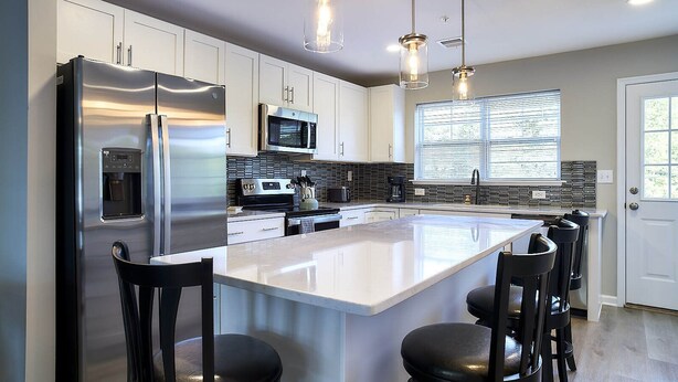 A modern kitchen with a large island, stainless steel appliances, and pendant lighting. - New Condo! Minutes from Sand Springs Golf Course & Wedding/Event Venue (Drums)