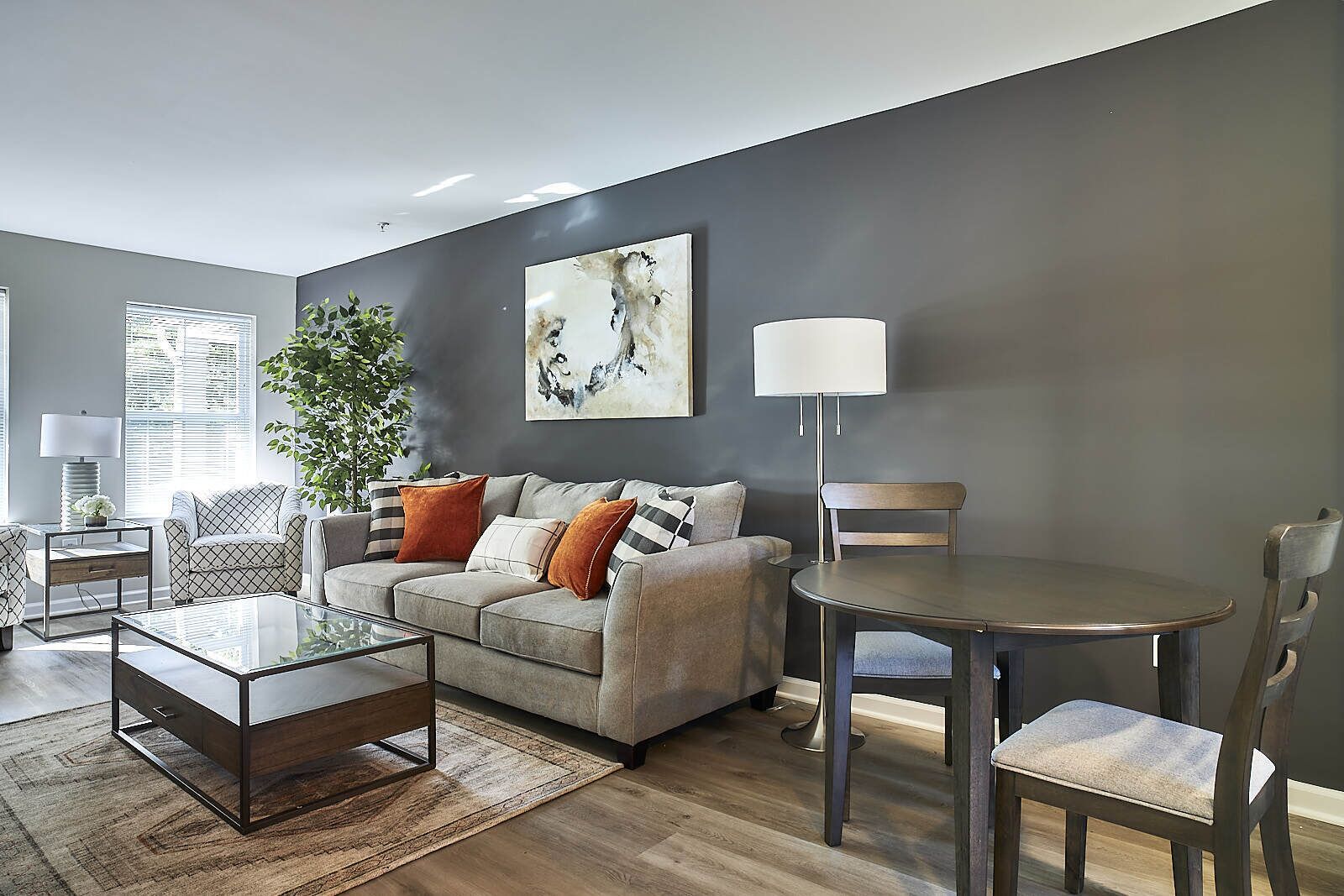 A modern living room with a sofa, coffee table, and a dining table with chairs.