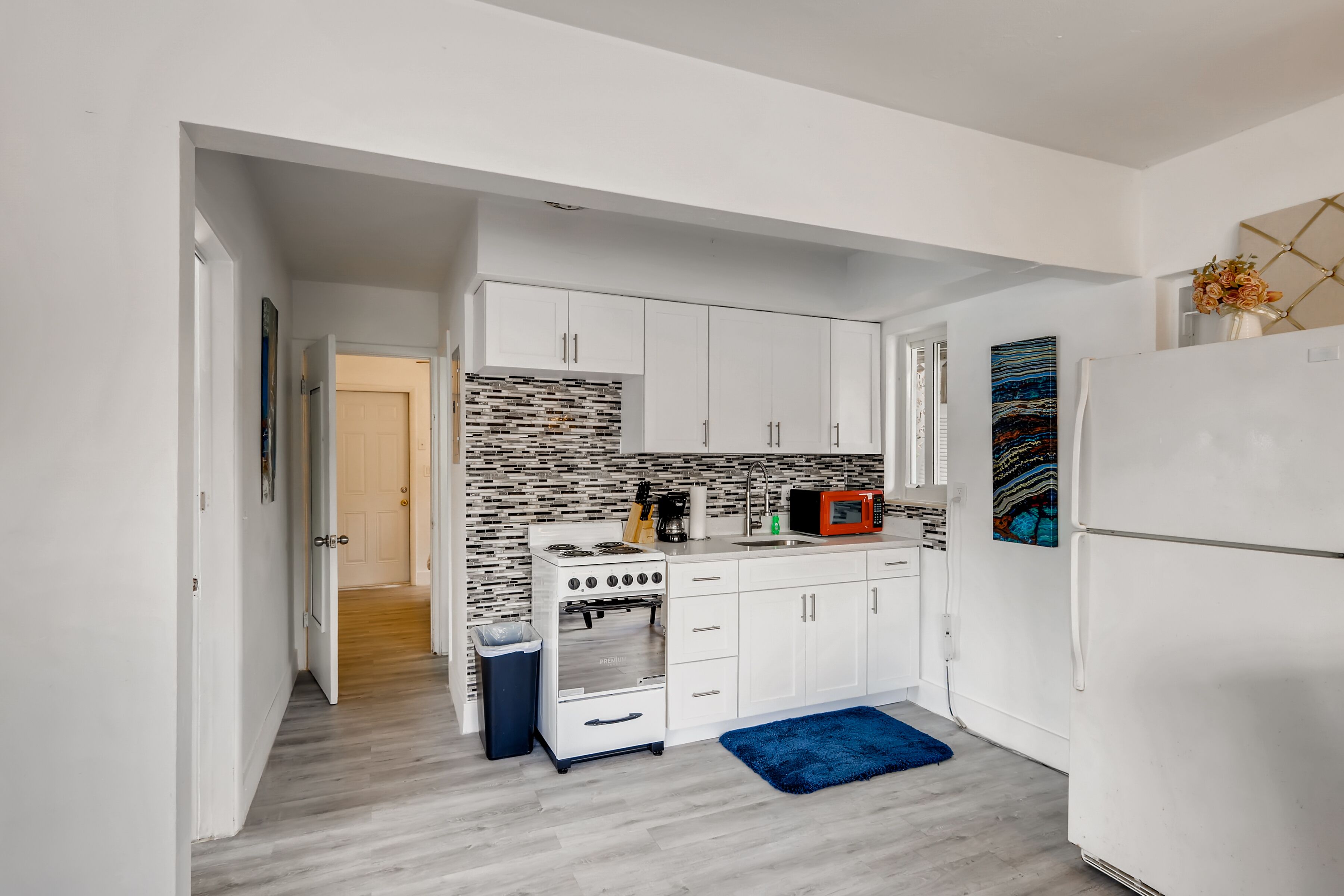 A modern kitchen with white cabinets, a stove, and a refrigerator.