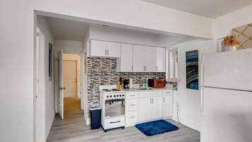 A modern kitchen with white cabinets, a stove, and a refrigerator.