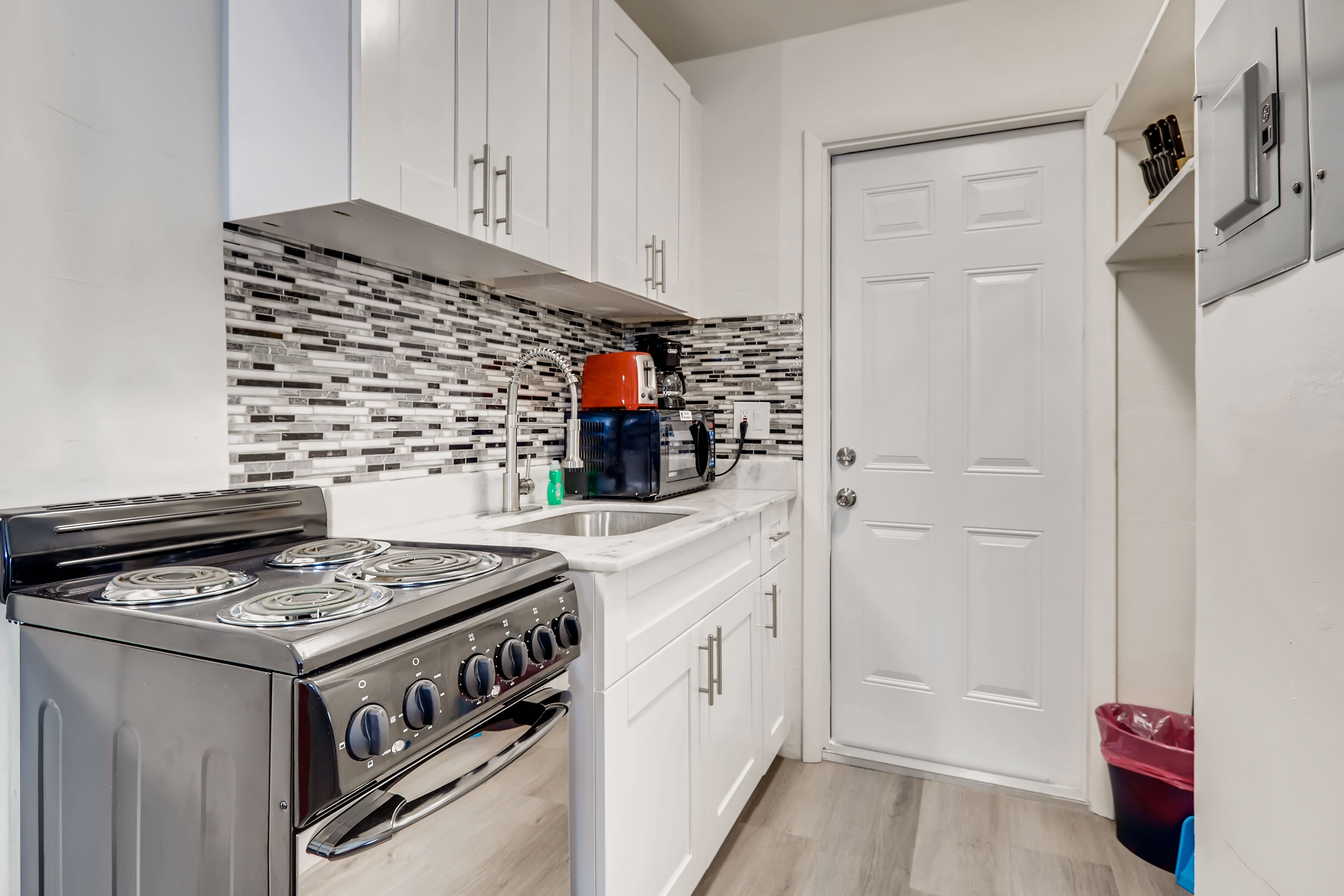 A modern kitchen with white cabinets, a black stove, and a tiled backsplash.