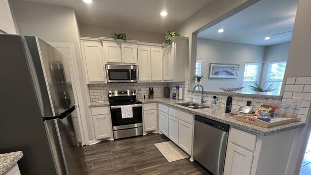 A modern kitchen with white cabinets, stainless steel appliances, and a granite countertop.