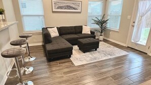 A living room with a sectional sofa, a coffee table, and a bar stool area.