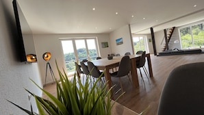 A spacious dining area with a large table and chairs, a modern ceiling with recessed lighting, and large windows offering a view of the outdoors. - Traumaussicht, Traumwanderungen, Viel zu Entdecken und Richtig Viel Platz!! (Daun)