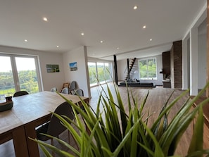 A spacious living area with a dining table, seating, a staircase, and a fireplace.
