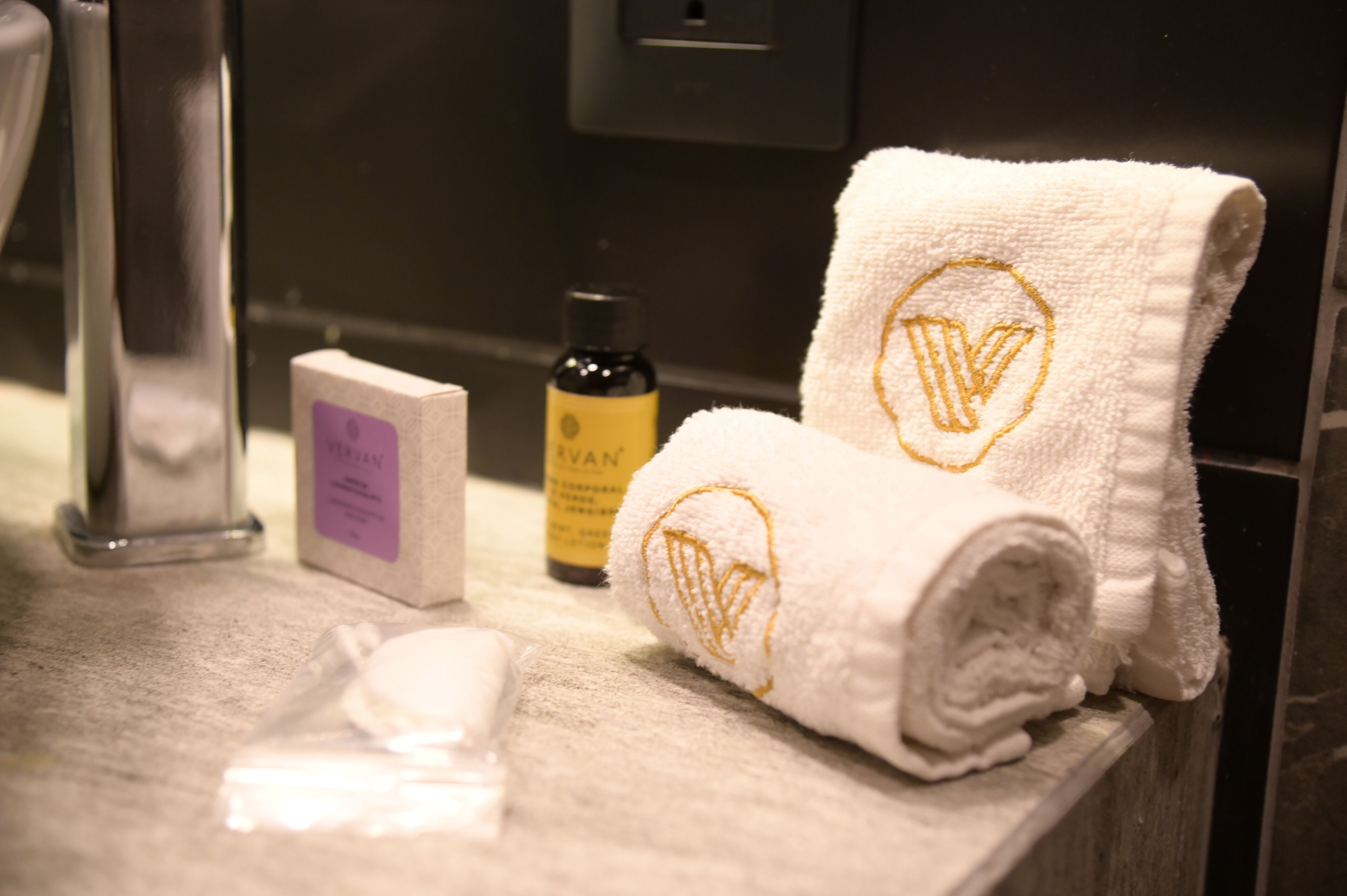 A bathroom with a white towel, a bottle of lotion, and a soap bar on the counter.