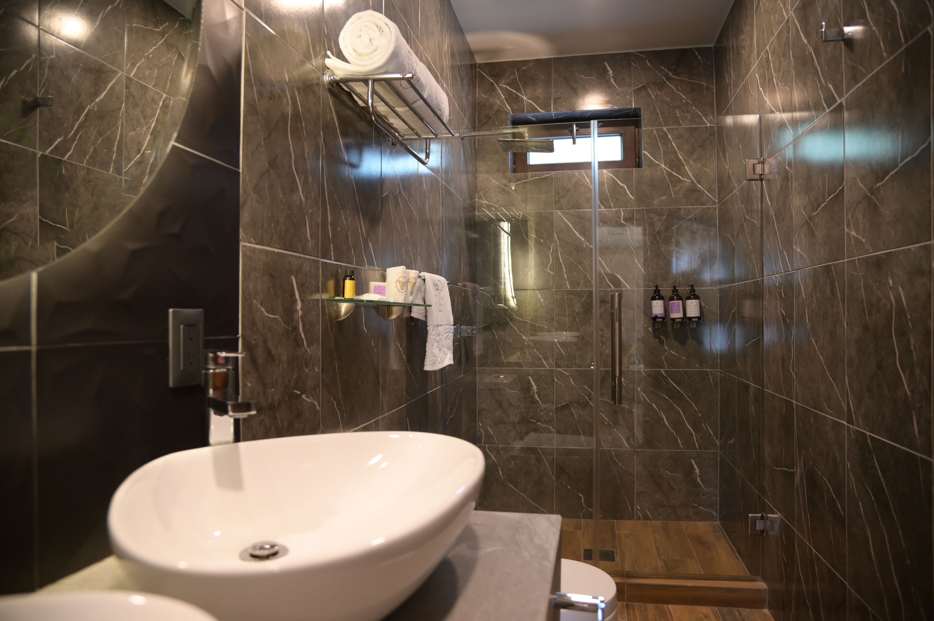 Une salle de bain moderne avec un grand lavabo blanc, une douche en verre et des murs en marbre.