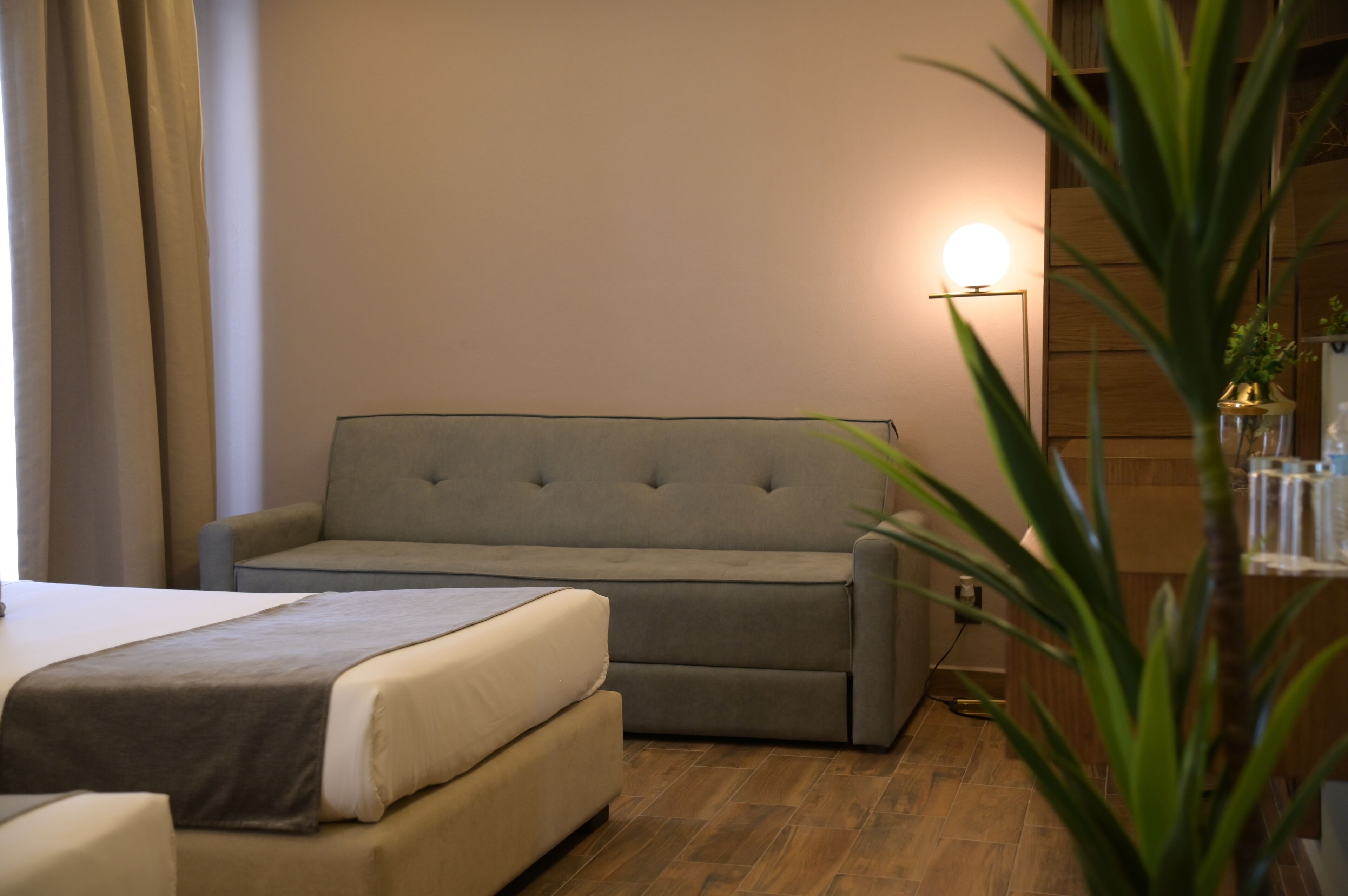 Una habitación de hotel moderna con un sofá cama, una mesita de noche y una lámpara.