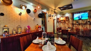 Un restaurante con pared de ladrillo, mesas de madera y una pantalla de televisión.