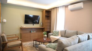 Una sala de estar moderna con un televisor de pantalla plana, muebles de madera y una mesa de centro redonda.