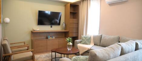 A modern living room with a flat-screen TV, wooden furniture, and a round coffee table.