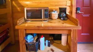 Un interno in legno con un forno a microonde su un tavolo di legno, un quadro incorniciato e una porta rossa.
