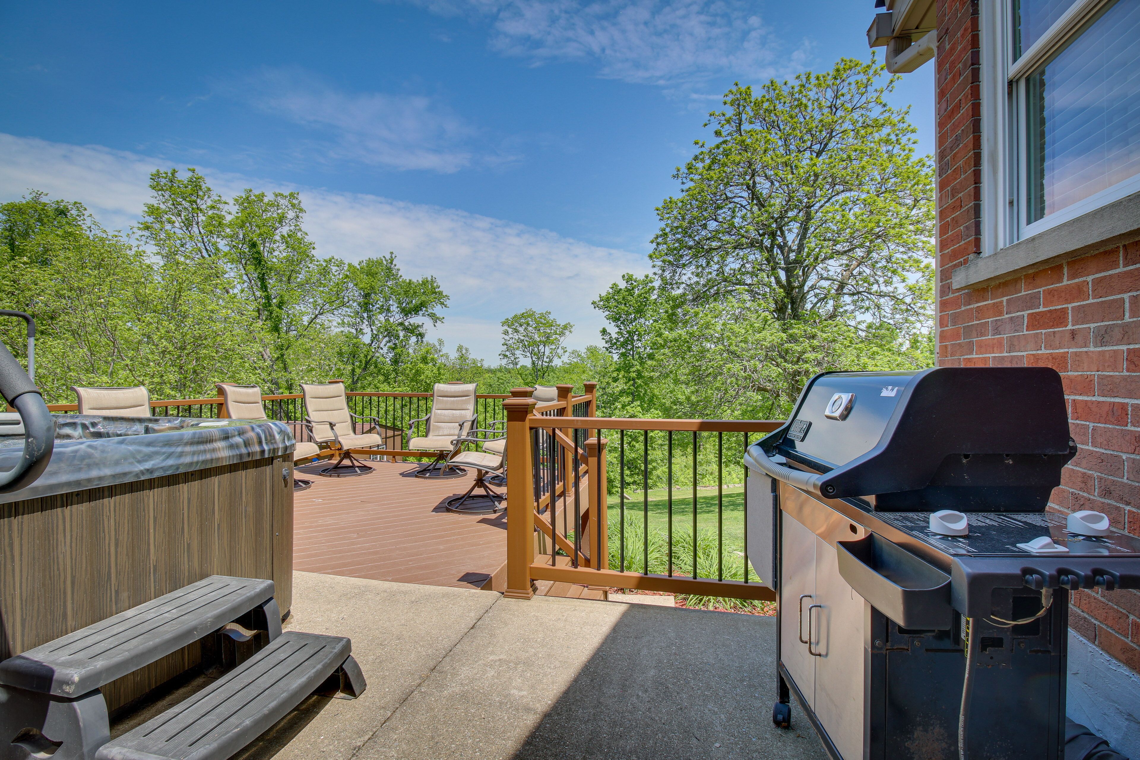 A patio with a hot tub, outdoor seating, and a barbecue grill.