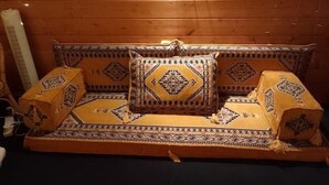 A wooden sofa with patterned cushions and a matching throw blanket. - Pilgrims of the Goddess - Cabin (Glastonbury)