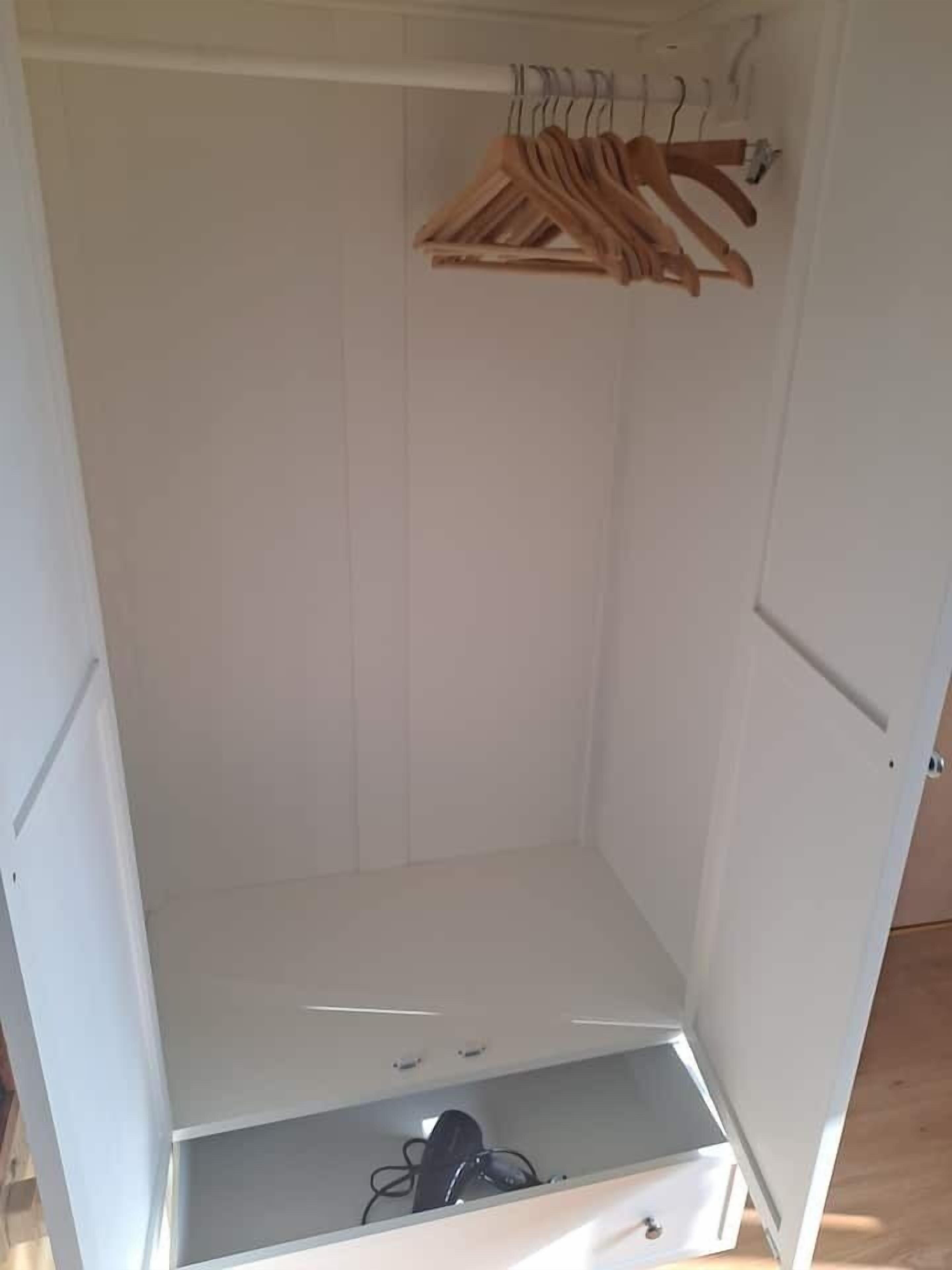 Une armoire blanche avec une section pour suspendre les vêtements et un tiroir en bas.