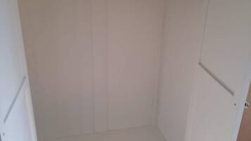 Une armoire blanche avec une section pour suspendre les vêtements et un tiroir en bas.