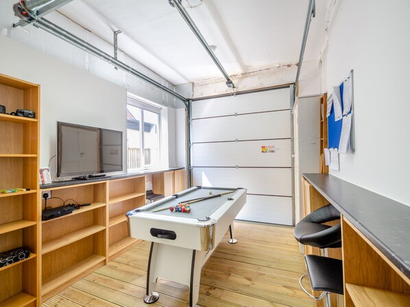 A room with a pool table, shelves, a television, and a window.