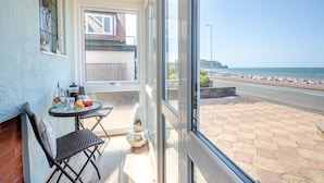 A balcony with a table, chairs, and a view of the sea.