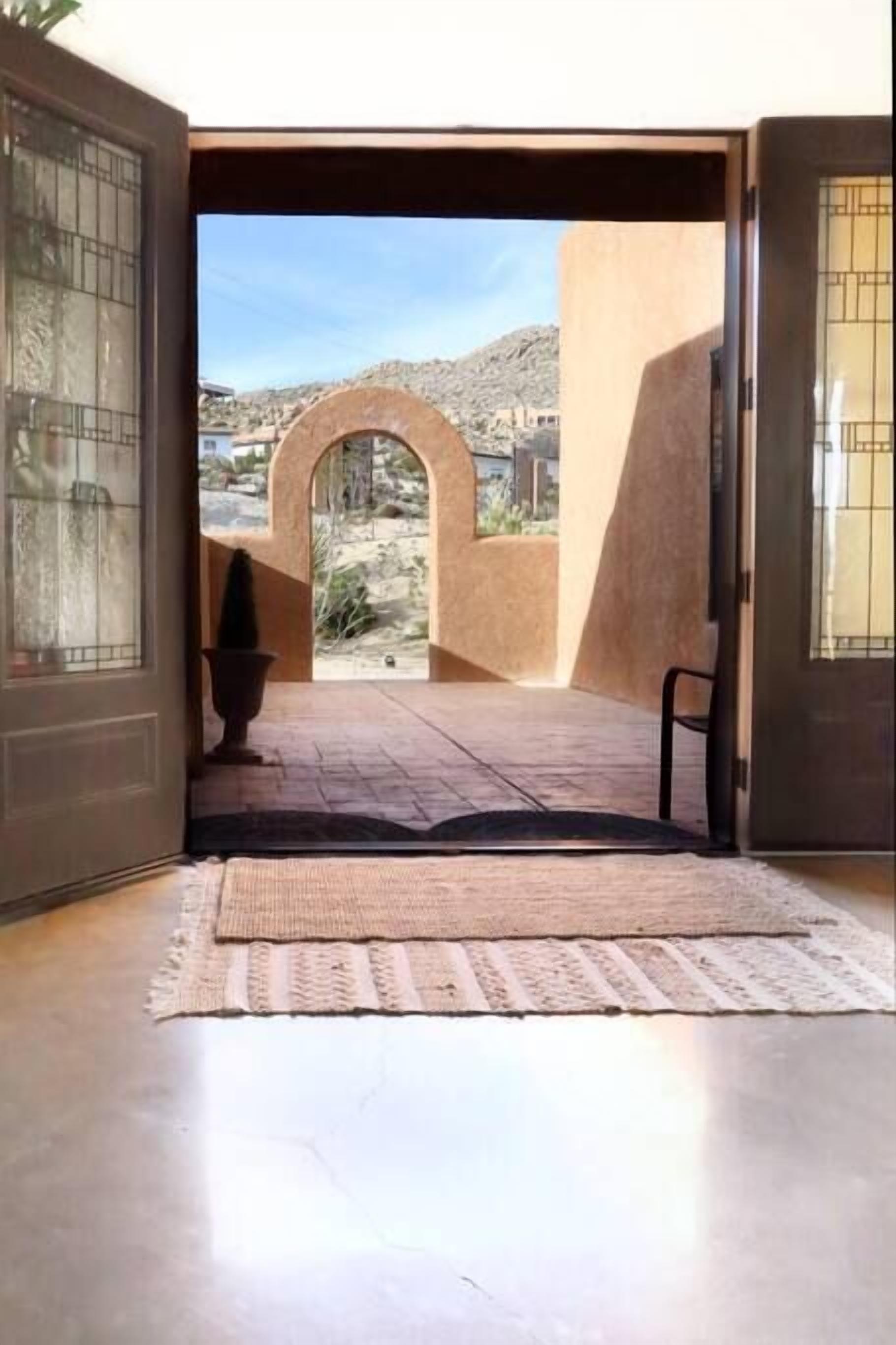An open doorway leading to a courtyard with a view of a mountainous landscape.