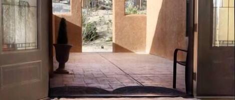 An open doorway leading to a courtyard with a view of a mountainous landscape.