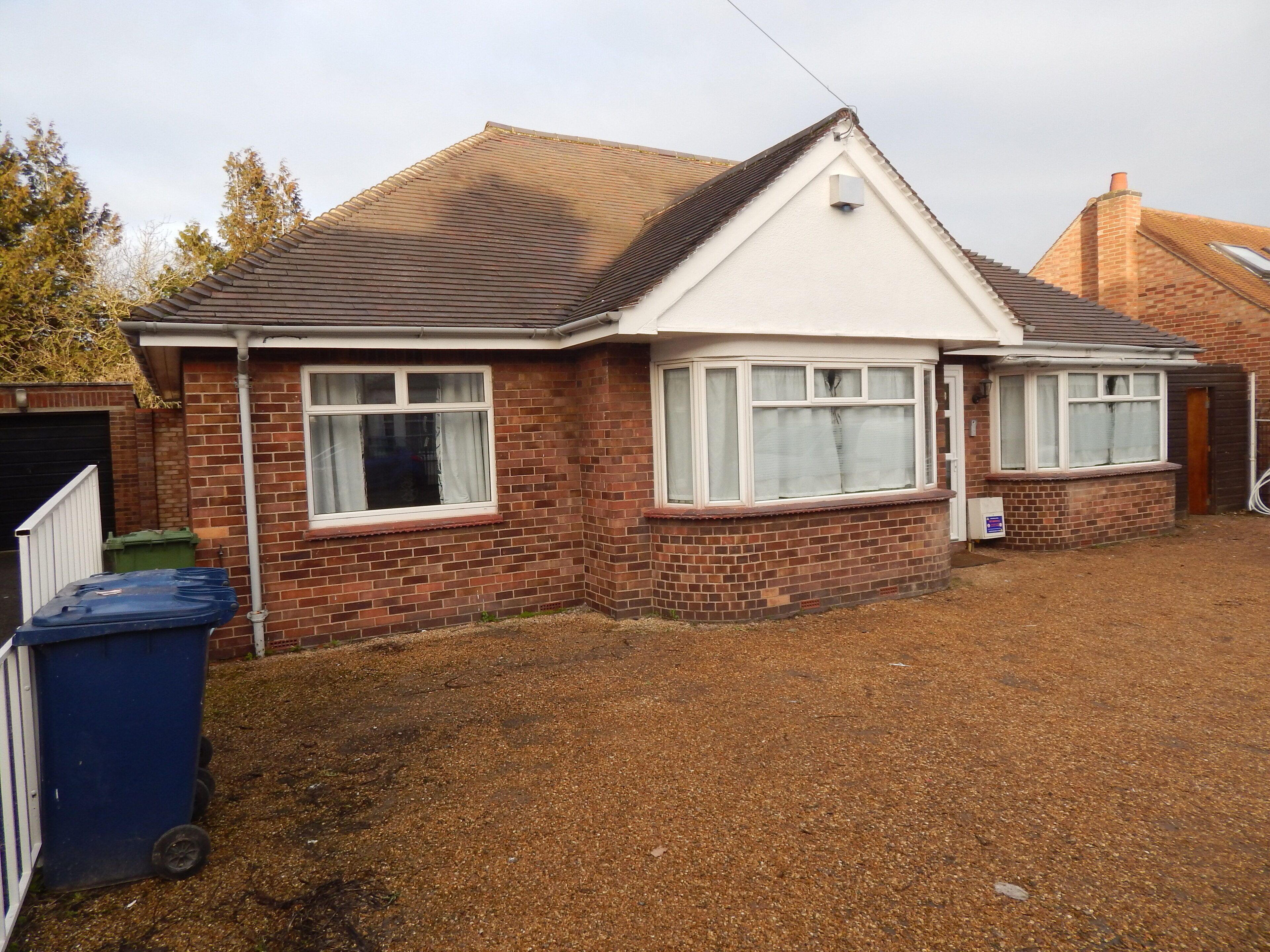 A two-story house with a brick exterior, a tiled roof, and a fenced yard.
