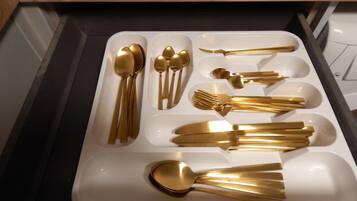 A drawer containing various gold-colored cutlery items including spoons, forks, and knives.