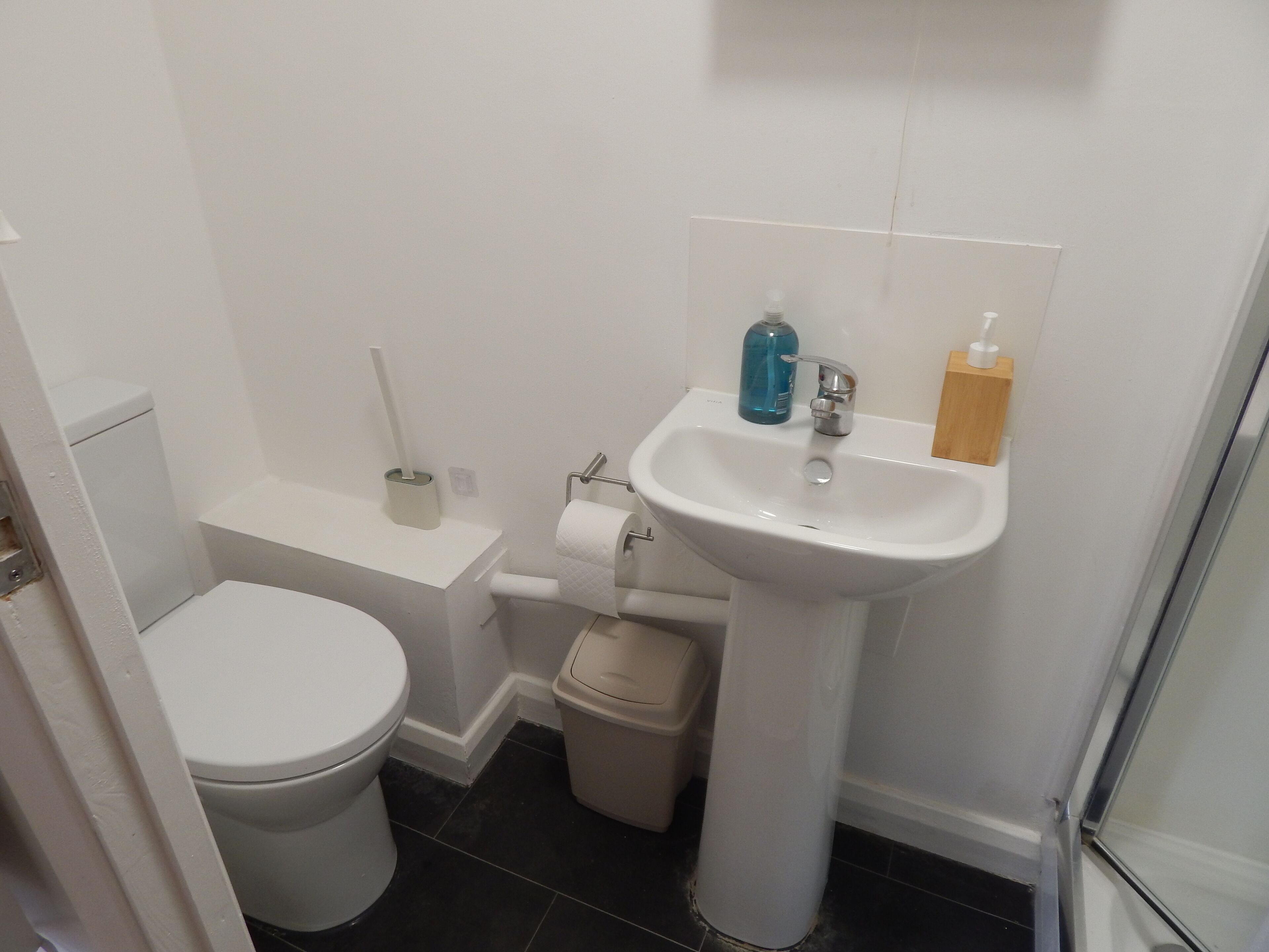 A small bathroom with a toilet, sink, and a trash bin.