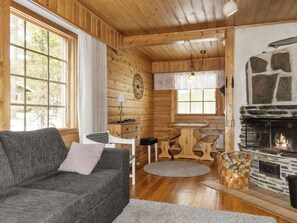 A cozy cabin interior with a sofa, a dining table, and a fireplace. - Susitupa 5 by Interhome (Salla)